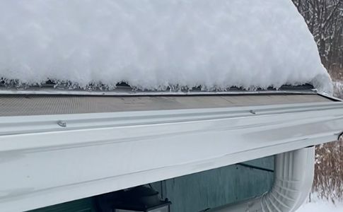 Residential home roofline with gutter in winter snow